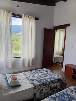 a bedroom with two beds and a large window at Lashara in Las Rabonas