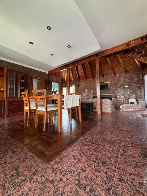 a dining room with a table and chairs and a fireplace at Casa Numerosa Vista al lago con Pileta Villa Carlos Paz in La Porteña