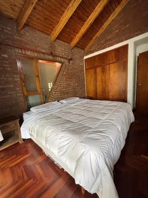 a large white bed in a room with a brick wall at Casa Numerosa Vista al lago con Pileta Villa Carlos Paz in La Porteña