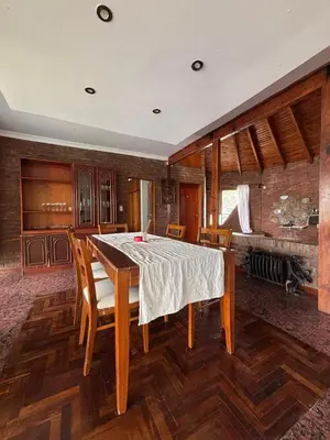 a dining room with a table and chairs and a fireplace at Casa Numerosa Vista al lago con Pileta Villa Carlos Paz in La Porteña