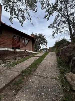 a dirt road next to a brick house at Casa Numerosa Vista al lago con Pileta Villa Carlos Paz in La Porteña