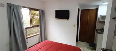a bedroom with a red bed and a window at Complejo Aguaducho in Cordoba