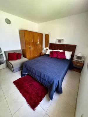 a bedroom with a blue bed with red pillows at Apartment 2 blocks from downtown Located at the back of the house in Villa Carlos Paz