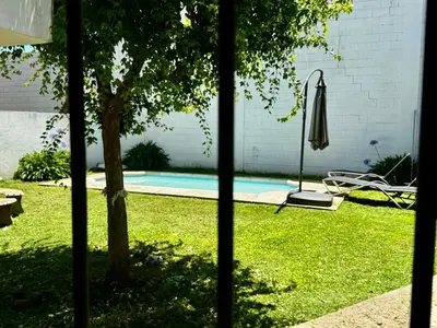 a backyard with a pool and a umbrella and a tree at Apartment 2 blocks from downtown Located at the back of the house in Villa Carlos Paz