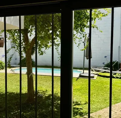 a window view of a yard with a tree and a pool at Apartment 2 blocks from downtown Located at the back of the house in Villa Carlos Paz