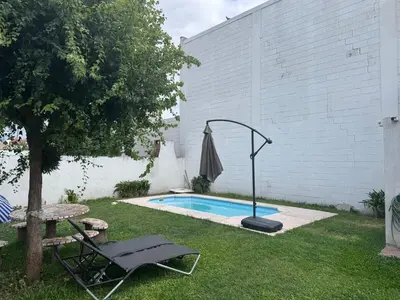 a swimming pool in a yard with a chair and an umbrella at Apartment 2 blocks from downtown Located at the back of the house in Villa Carlos Paz