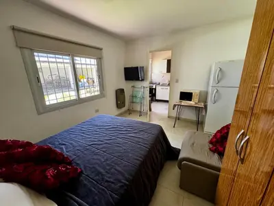 a bedroom with a bed and a living room at Apartment 2 blocks from downtown Located at the back of the house in Villa Carlos Paz