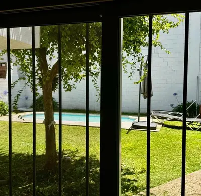 a window view of a yard with a tree and a pool at Apartment 2 blocks from downtown Located at the back of the house in Villa Carlos Paz
