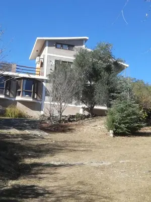 a house with trees in front of it at Mirador De Las Sierras in Villa Serranita