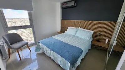 a bedroom with a bed and a chair and a window at The Thirty Floor Sky Suite in Cordoba