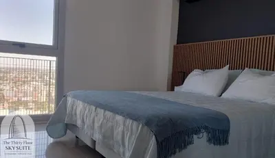 a bedroom with a large bed with a large window at The Thirty Floor Sky Suite in Cordoba