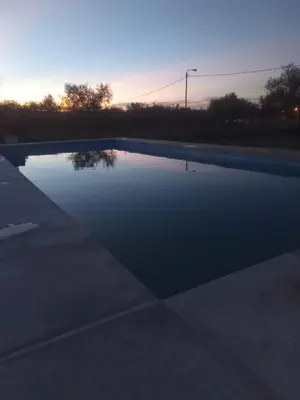 a swimming pool with a sunset in the background at Casa con pileta mina clavero in Mina Clavero