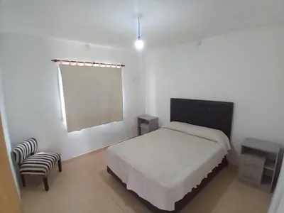 a bedroom with a bed and a chair and a window at Casa con pileta mina clavero in Mina Clavero