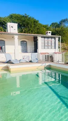 a swimming pool with blue chairs and a house at Casa- Villa Parque Siquiman in Villa Parque Siquiman