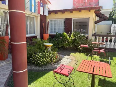 a yard with a red bench and chairs in front of a house at Hotel Ideal vcp in Villa Carlos Paz