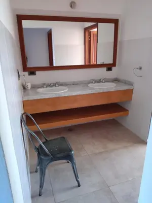 a bathroom with two sinks and a chair and a mirror at Casa lago dique los molinos in La Estancia