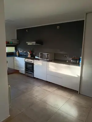 a kitchen with white cabinets and a black wall at Casa lago dique los molinos in La Estancia