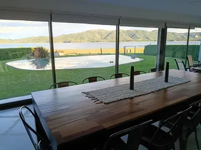 a long wooden table with chairs and a large window at Casa lago dique los molinos in La Estancia