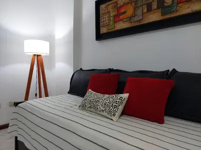 a bed with red and white pillows and a lamp at Mirasol in Villa Carlos Paz