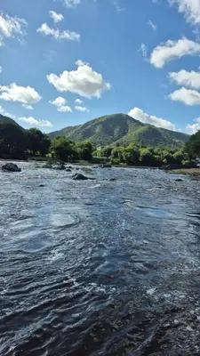 a view of a river with mountains in the background at La Casa del Gran Nogal in Villa Carlos Paz