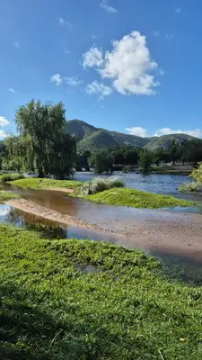 a body of water with trees and hills in the background at La Casa del Gran Nogal in Villa Carlos Paz