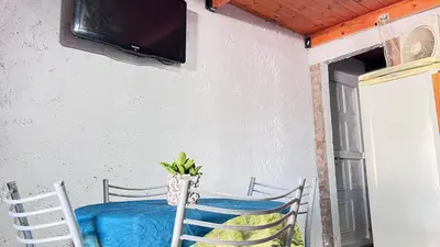 a table with two chairs and a tv on a wall at Monoambiente a metros del río in Tanti
