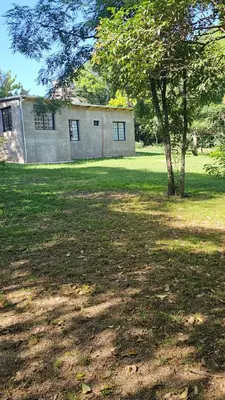 a building in the middle of a field with a tree at Chalet alaniz salinas in Cordoba
