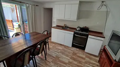 a kitchen with a wooden table and a table and a stove at Departamento Don Pipo in Villa Carlos Paz