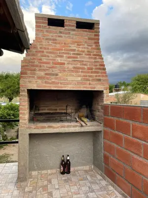a brick oven with three bottles sitting on a patio at Faroflor departamento in Arroyo de Los Patos