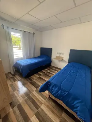 a bedroom with a blue bed and a window at Cabañas Colibri in Merlo