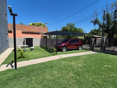 a red suv parked under a canopy in a yard at Cabañas Colibri in Merlo