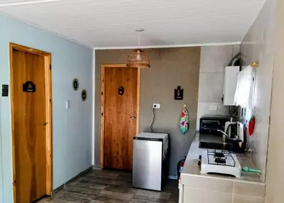 a small kitchen with a refrigerator and a door at La Berilde in La Población