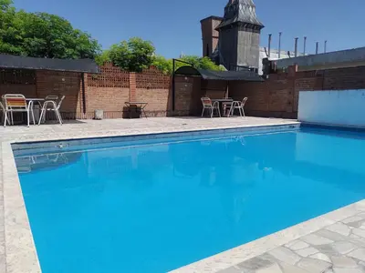 a large blue swimming pool with chairs and a table at Hotel Dunes in Villa Carlos Paz