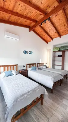 two beds in a room with wooden ceilings at Señal de Amor in Villa General Belgrano