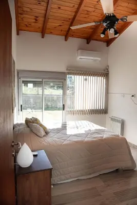 a bedroom with a large bed with a ceiling fan at Señal de Amor in Villa General Belgrano