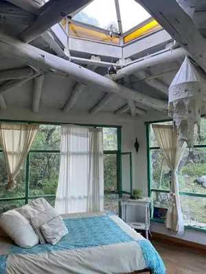 a bedroom with a bed in a room with windows at Cosmika, eco casa de Cosmika, eco casa de montaña in Las Calles