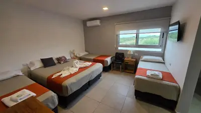 a hotel room with three beds and a window at Complejo Gran Chacha in Tanti