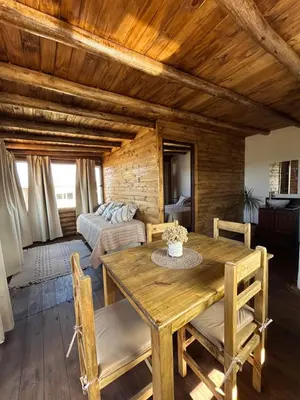 a living room with a wooden table and a bed at Aruma Cabañas in Tanti