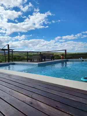 a pool with a wooden deck and a view of the field at Aruma Cabañas in Tanti
