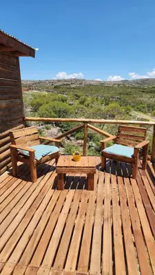 a wooden deck with two benches and a table at Aruma Cabañas in Tanti