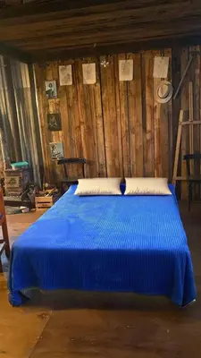 a blue bed in a room with a wooden wall at Eco Refugio de Montaña en San Javier, Traslasierra in San Javier