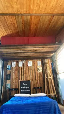 a bed in a room with a wooden wall at Eco Refugio de Montaña en San Javier, Traslasierra in San Javier