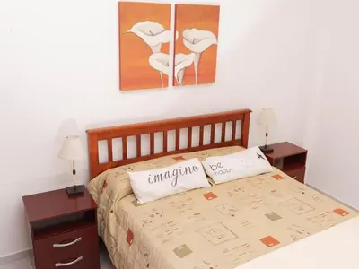 a bedroom with a bed with two tables and two paintings at Depto 1 in Villa Carlos Paz