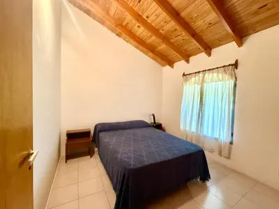a bedroom with a blue bed and a window at Casa Los Prados Mina Clavero in Mina Clavero