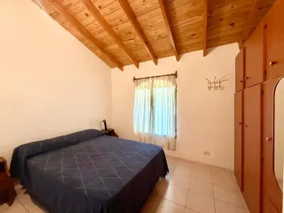 a bedroom with a blue bed and a window at Casa Los Prados Mina Clavero in Mina Clavero