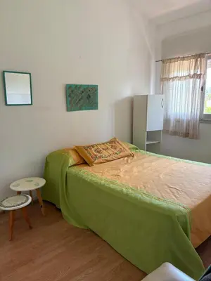 a bedroom with a green bed and a table at Casa centro in Villa Carlos Paz