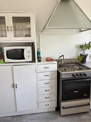 a kitchen with a stove and a microwave at Casa centro in Villa Carlos Paz