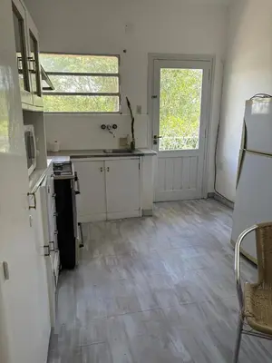 a kitchen with white cabinets and a window and a door at Casa centro in Villa Carlos Paz