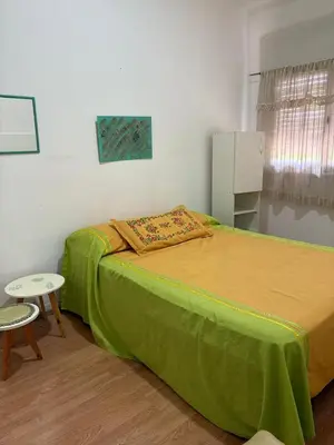 a bedroom with a green bed and a table at Casa centro in Villa Carlos Paz