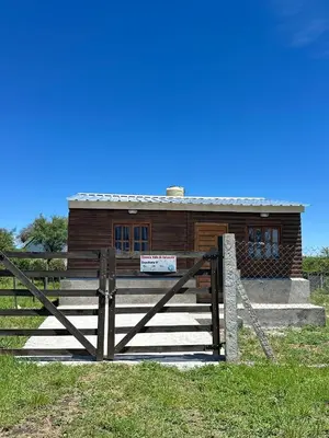 a wooden house with a fence in front of it at Cabaña Aguaribay in Villa Anizacate